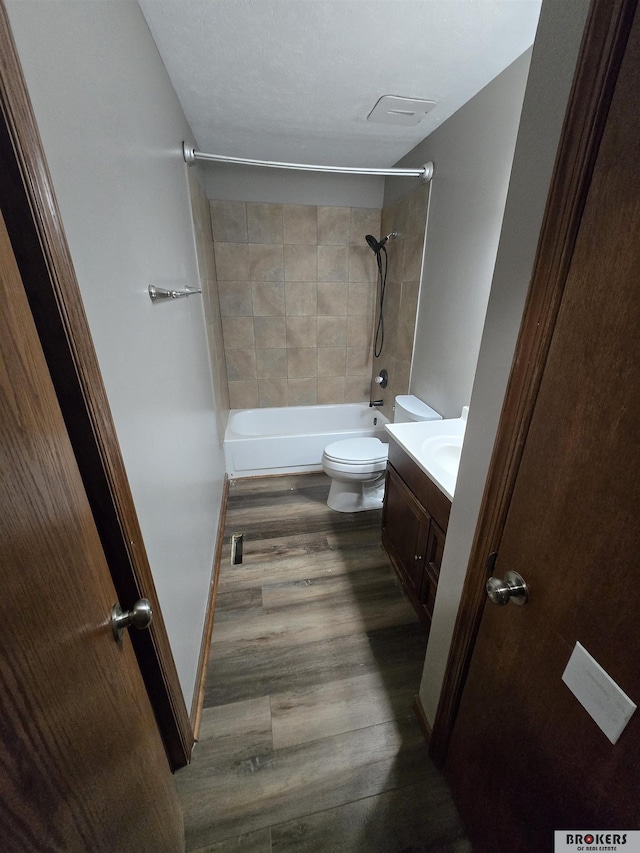 full bathroom featuring toilet, tiled shower / bath combo, wood-type flooring, and vanity