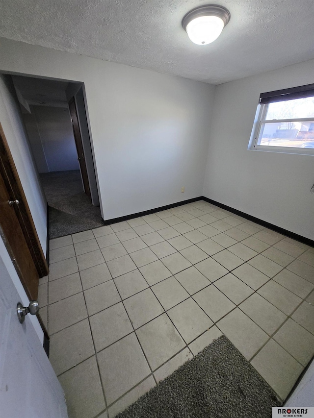 tiled spare room featuring a textured ceiling