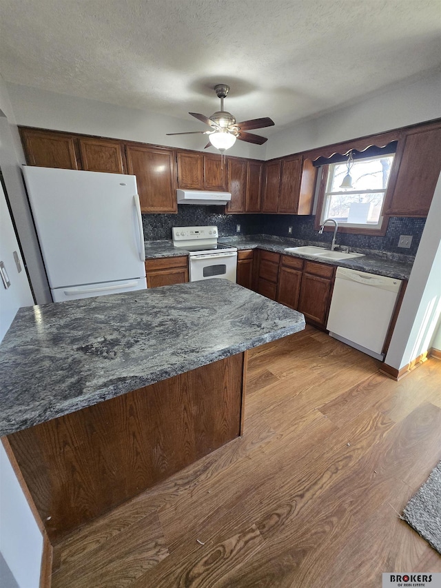 kitchen with light hardwood / wood-style floors, ceiling fan, white appliances, dark stone counters, and sink