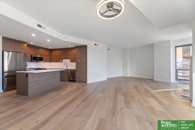 kitchen with light hardwood / wood-style flooring, appliances with stainless steel finishes, sink, and a center island