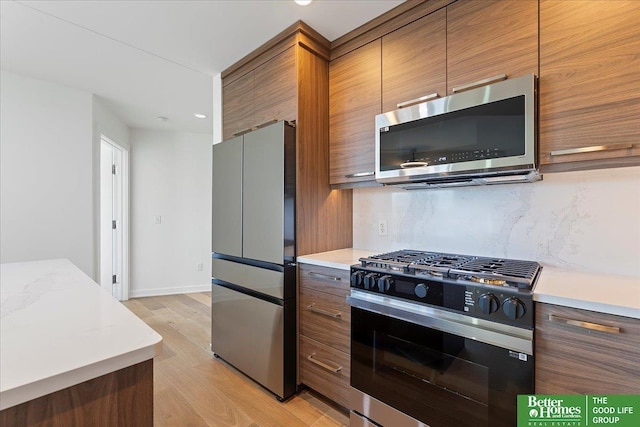 kitchen featuring appliances with stainless steel finishes, light hardwood / wood-style floors, and tasteful backsplash