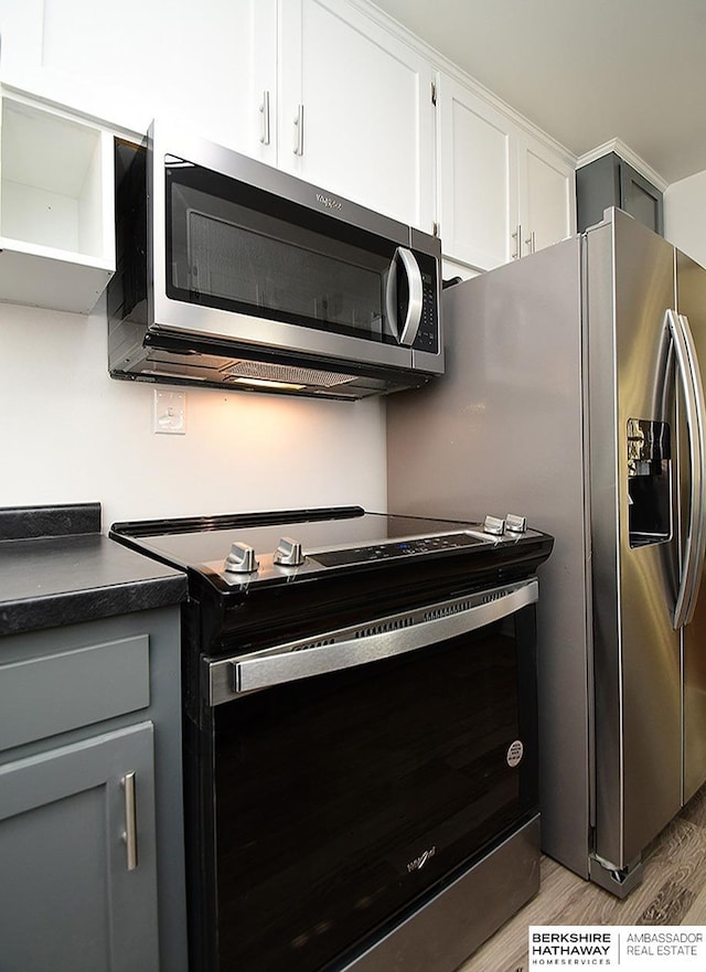 kitchen with white cabinets, light hardwood / wood-style flooring, and appliances with stainless steel finishes