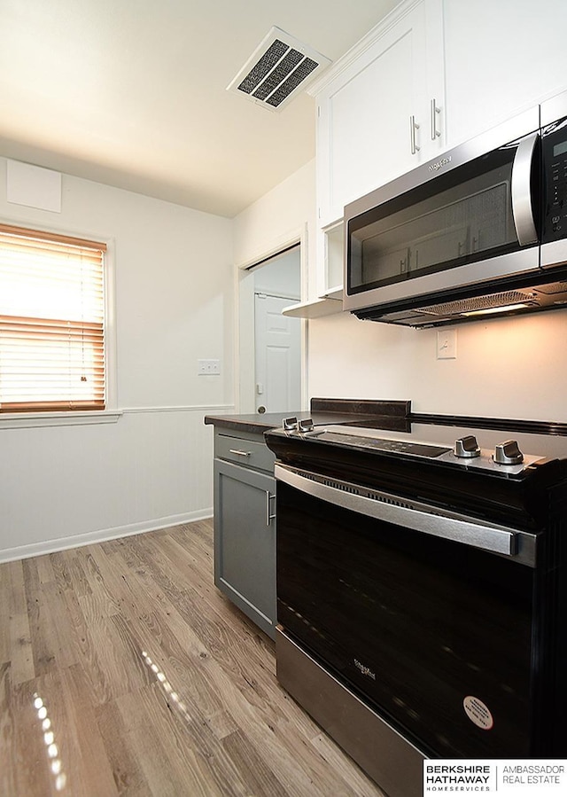 kitchen with stainless steel appliances, gray cabinetry, light hardwood / wood-style floors, and white cabinets