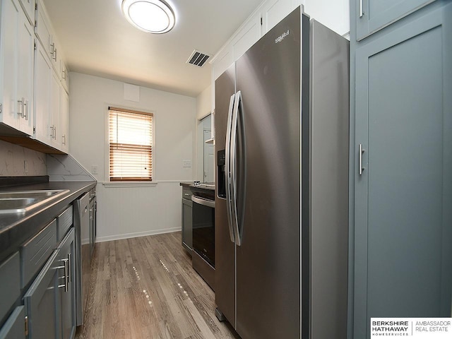 kitchen with white cabinets, appliances with stainless steel finishes, light hardwood / wood-style flooring, and sink