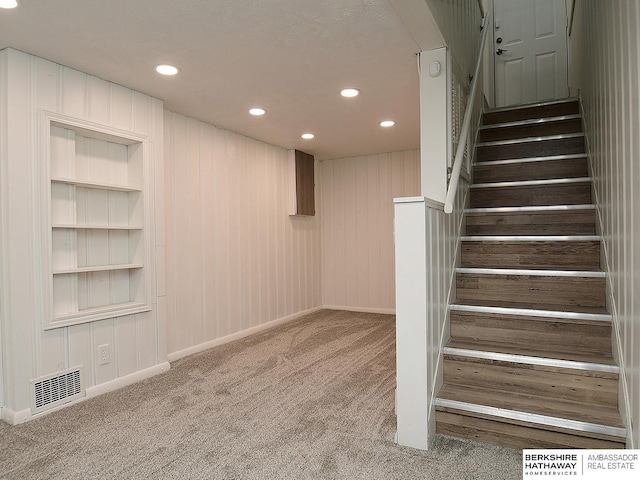 stairway with built in shelves and carpet flooring