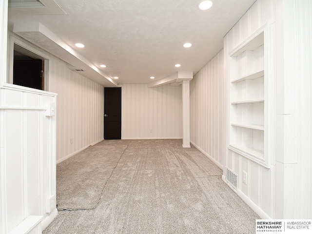 carpeted empty room with built in shelves and a textured ceiling