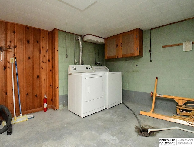 laundry area with cabinets, washer and dryer, and wooden walls