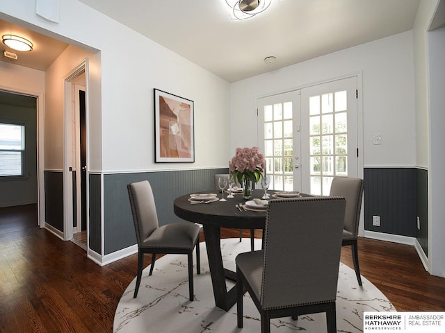 dining area with wood walls, dark wood-type flooring, and french doors