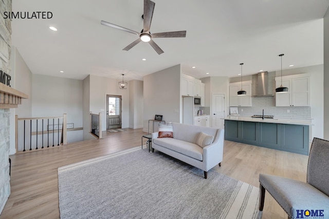 living room with light hardwood / wood-style floors, sink, and ceiling fan with notable chandelier