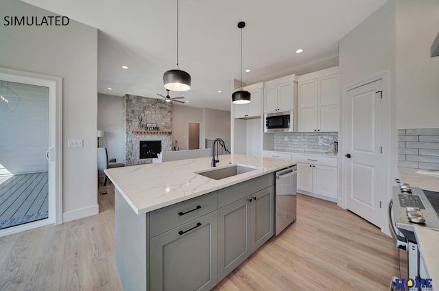 kitchen featuring a kitchen island with sink, built in microwave, light stone countertops, stainless steel dishwasher, and sink