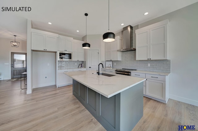 kitchen with stainless steel appliances, an island with sink, white cabinets, and wall chimney range hood