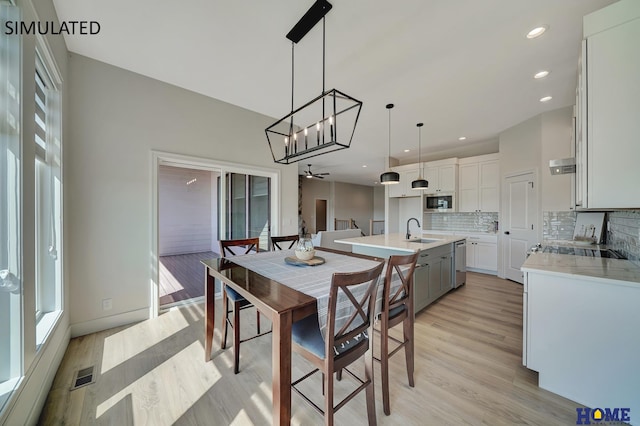 dining area featuring light hardwood / wood-style floors, plenty of natural light, sink, and ceiling fan with notable chandelier