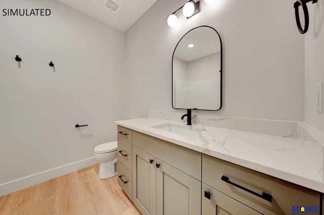 bathroom featuring wood-type flooring, toilet, and vanity