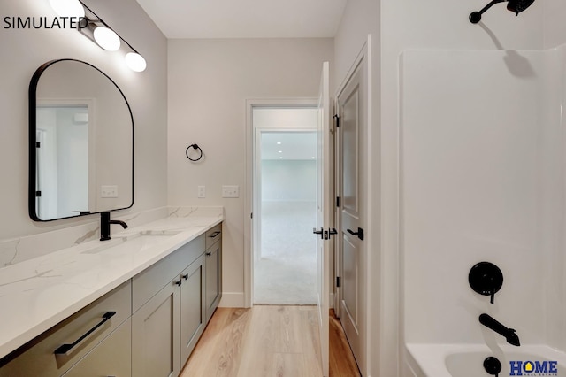 bathroom with washtub / shower combination, hardwood / wood-style flooring, and vanity