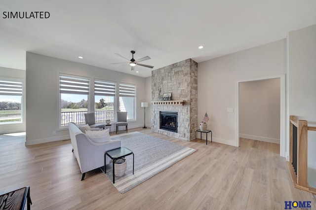 living room with light wood-type flooring, ceiling fan, and a fireplace