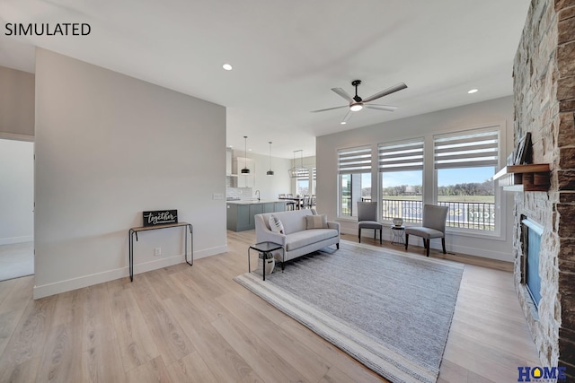 living room featuring ceiling fan, a fireplace, and light hardwood / wood-style flooring