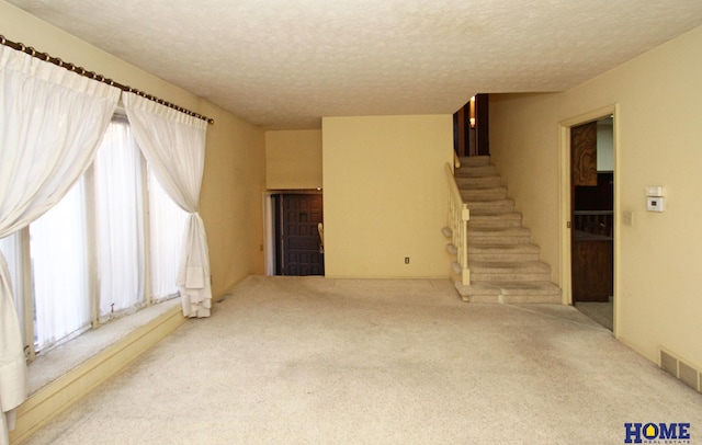 interior space featuring light colored carpet and a textured ceiling