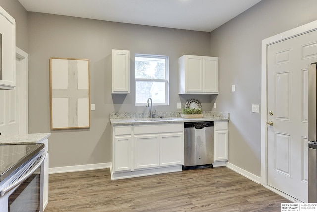 kitchen with light stone countertops, white cabinetry, stainless steel appliances, light hardwood / wood-style floors, and sink