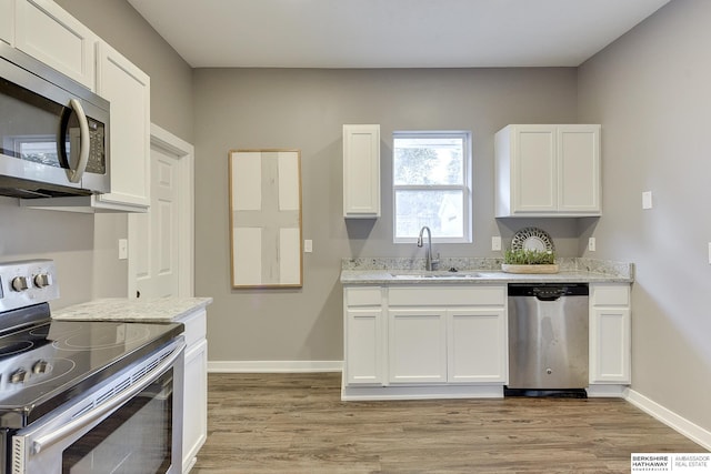 kitchen with light stone countertops, sink, white cabinetry, and stainless steel appliances