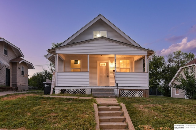 bungalow with covered porch and a lawn