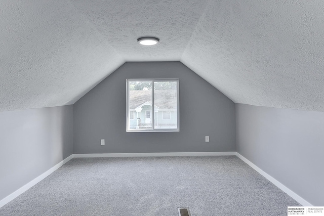 bonus room with lofted ceiling, carpet floors, and a textured ceiling