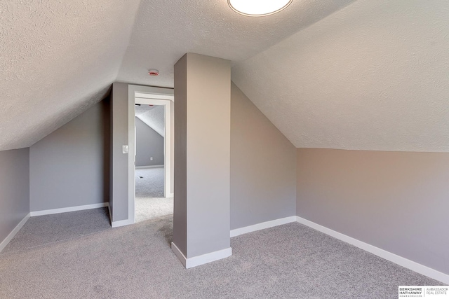 bonus room with light colored carpet, a textured ceiling, and lofted ceiling