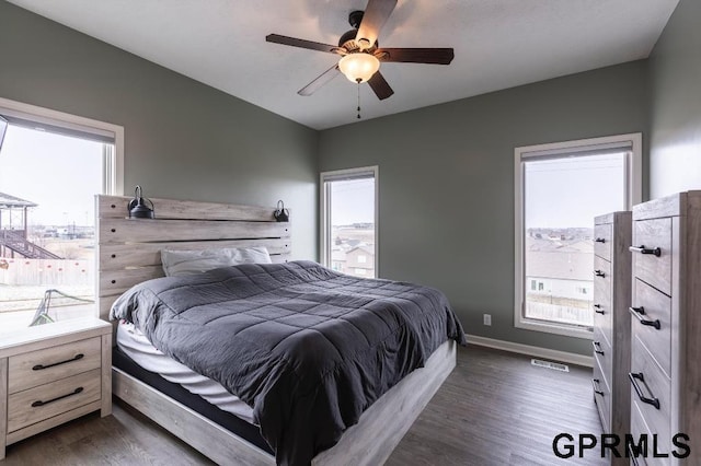 bedroom with ceiling fan, dark hardwood / wood-style floors, and multiple windows