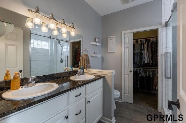 bathroom featuring a shower with door, hardwood / wood-style floors, toilet, and vanity