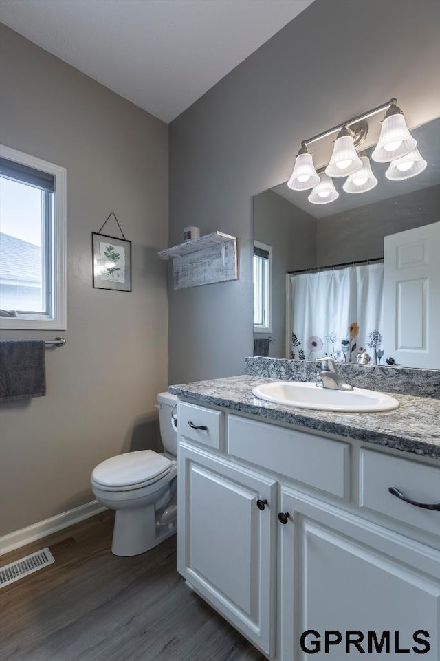 bathroom with toilet, hardwood / wood-style flooring, vanity, and curtained shower