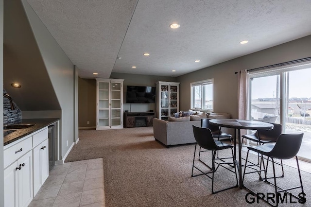 dining space with a textured ceiling, light colored carpet, and sink