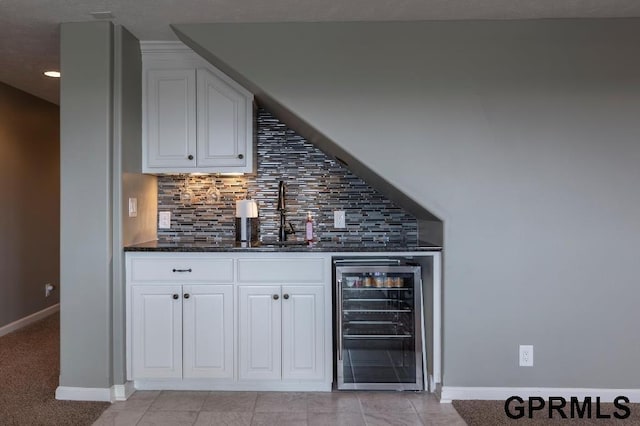 bar featuring white cabinets, beverage cooler, backsplash, and dark stone counters