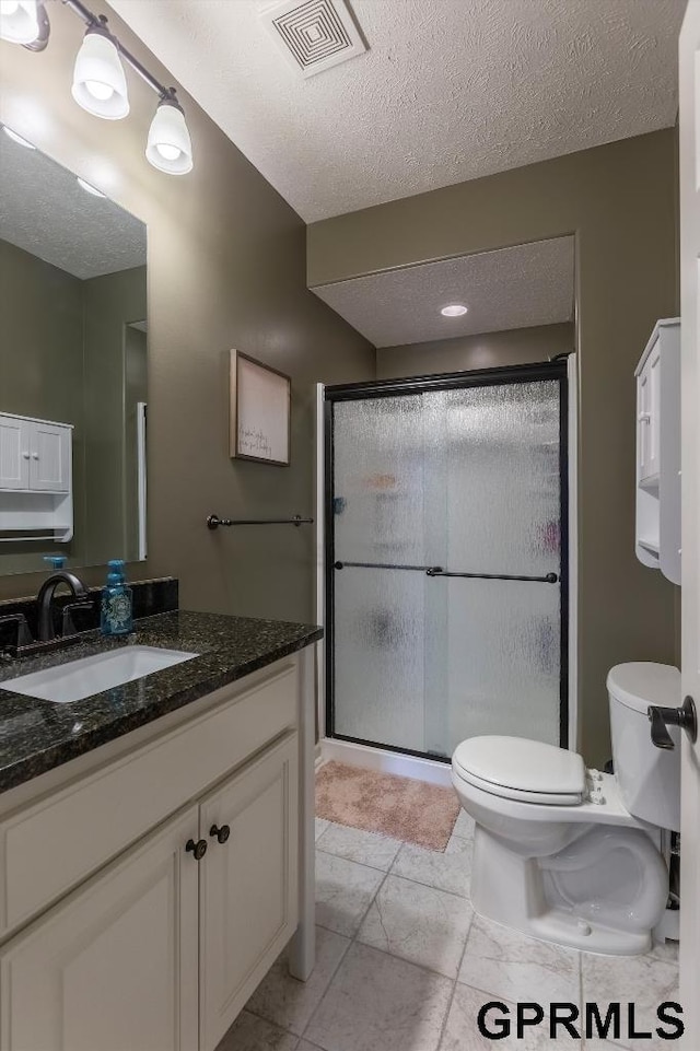 bathroom with toilet, a shower with door, and a textured ceiling