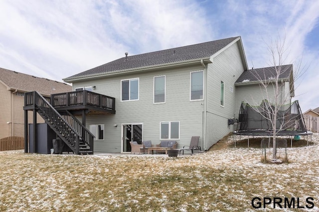 rear view of property featuring a deck, outdoor lounge area, and a trampoline