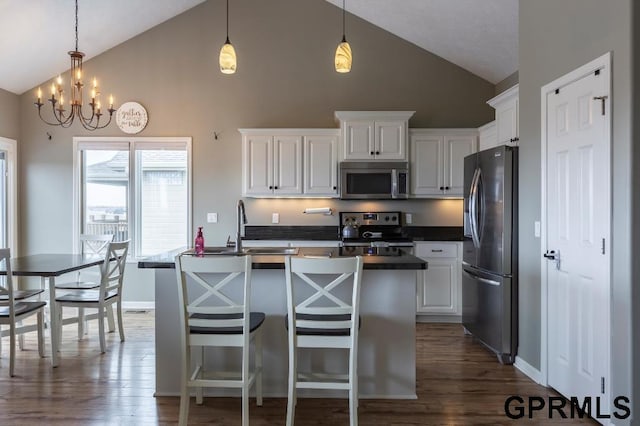 kitchen with appliances with stainless steel finishes, pendant lighting, white cabinets, and sink