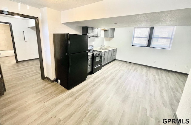 kitchen with a textured ceiling, sink, light hardwood / wood-style flooring, and black appliances