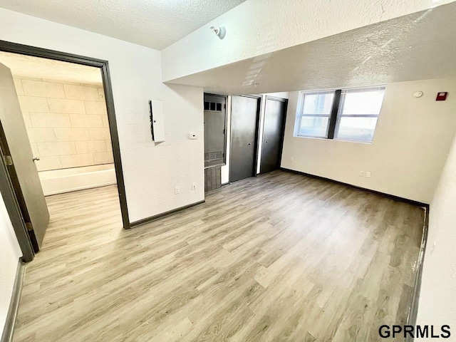 unfurnished room featuring a textured ceiling and light hardwood / wood-style floors