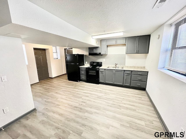 kitchen with gray cabinetry, a textured ceiling, black appliances, light hardwood / wood-style flooring, and sink