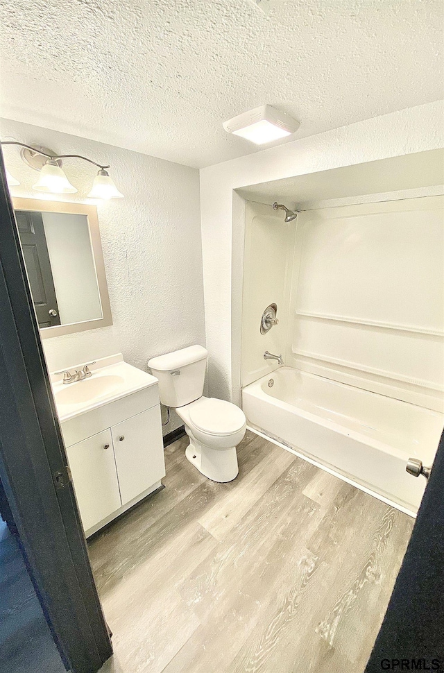 full bathroom with toilet, bathtub / shower combination, wood-type flooring, a textured ceiling, and vanity