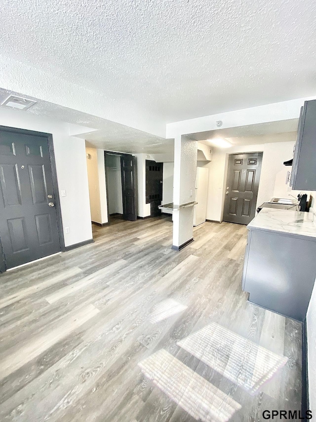 interior space with a textured ceiling and light hardwood / wood-style floors