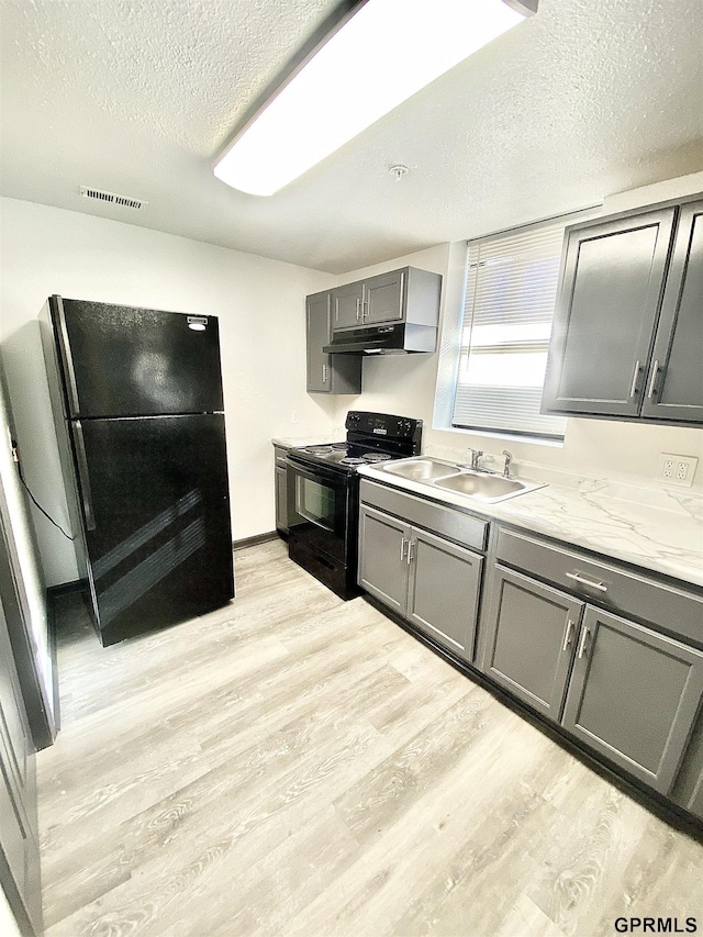 kitchen with sink, light wood-type flooring, black appliances, and gray cabinetry