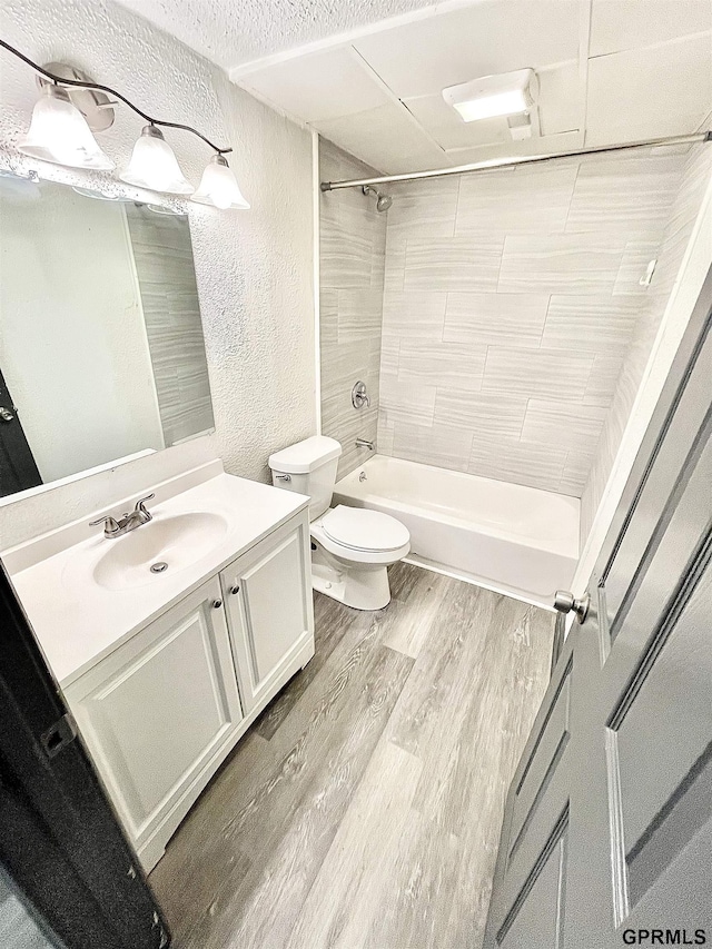 full bathroom with toilet, tiled shower / bath combo, wood-type flooring, and vanity