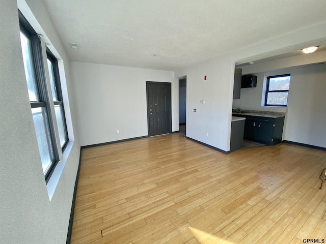 unfurnished living room with a textured ceiling and light hardwood / wood-style floors