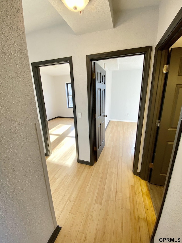 hall featuring a textured ceiling and light hardwood / wood-style floors