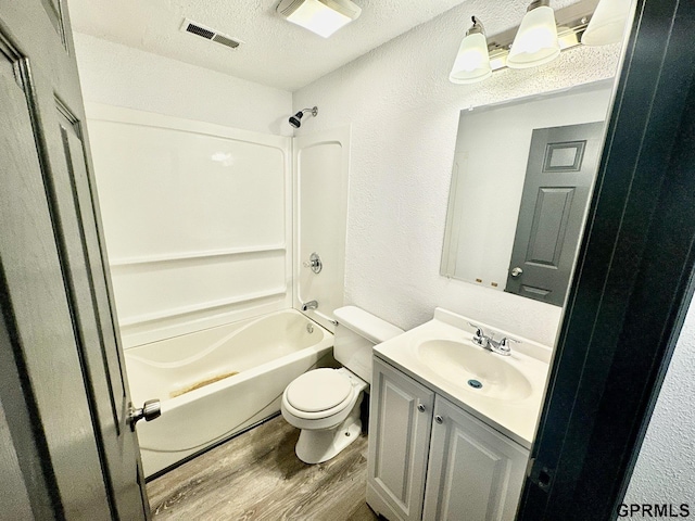 full bathroom featuring toilet, wood-type flooring, a textured ceiling, shower / bathtub combination, and vanity