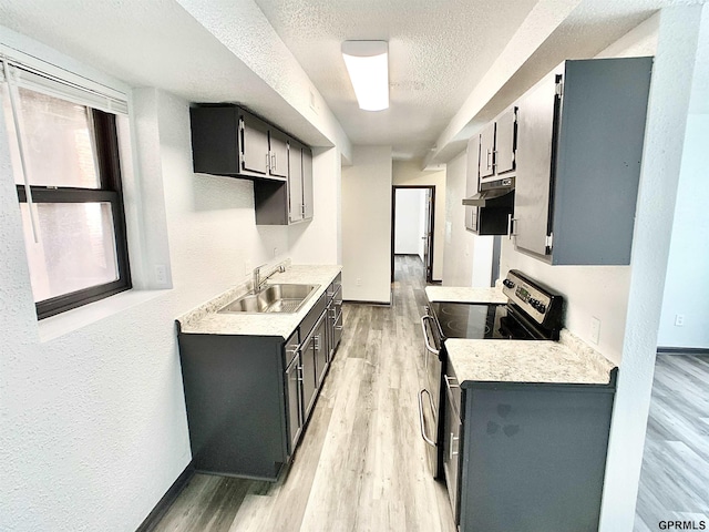 kitchen featuring a textured ceiling, light hardwood / wood-style floors, stainless steel electric range oven, and sink