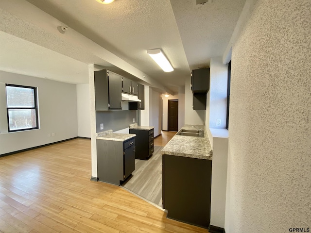 kitchen featuring light wood-type flooring, a textured ceiling, and sink