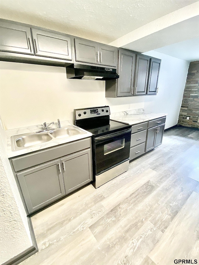 kitchen with a textured ceiling, stainless steel range with electric cooktop, sink, gray cabinets, and light hardwood / wood-style flooring