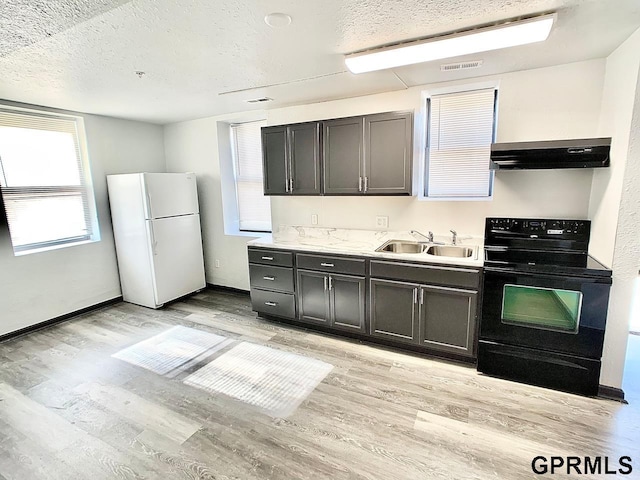 kitchen featuring a textured ceiling, black range with electric stovetop, white fridge, sink, and light wood-type flooring