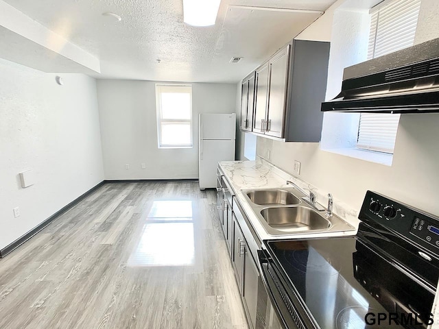 kitchen featuring a textured ceiling, white fridge, sink, electric range, and range hood