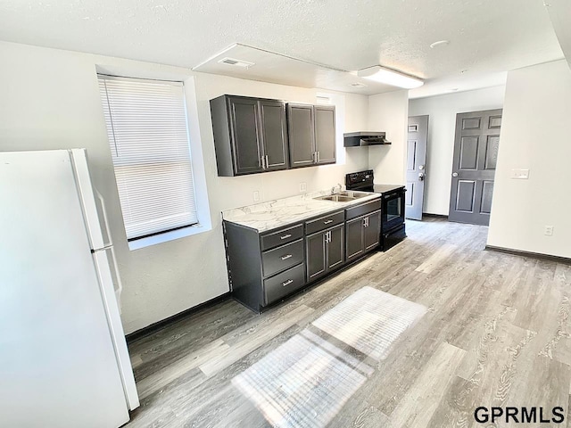 kitchen featuring white fridge, light hardwood / wood-style floors, a textured ceiling, black / electric stove, and sink